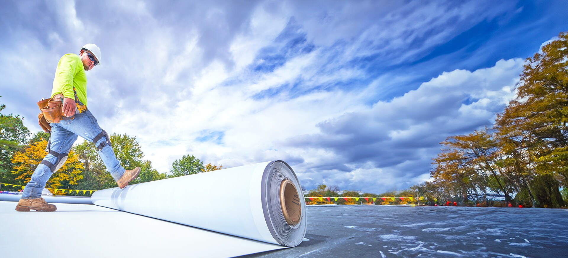 GAF certified commercial roofing contractor rolling out a commercial roofing membrane