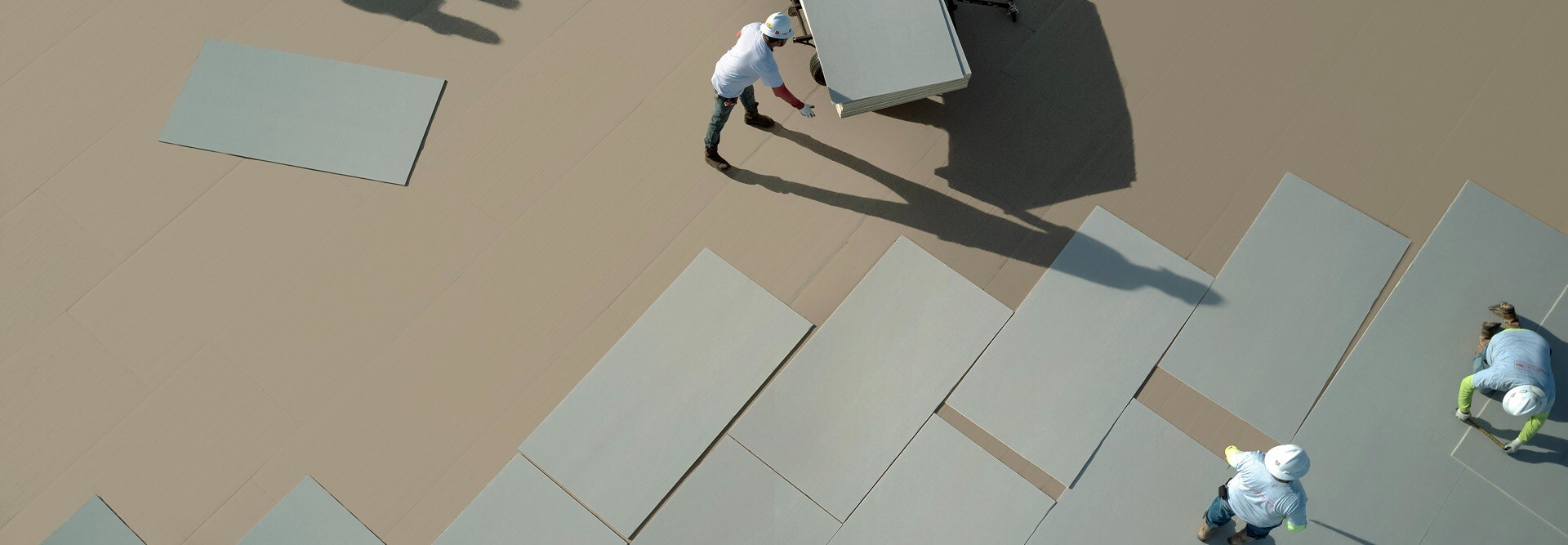 Commercial roofing contractors laying out EnergyGuard NH polyiso materials