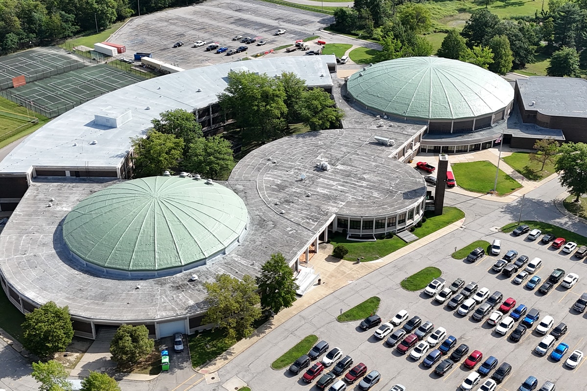 Aerial view of Normandy High School campus showing both restored Patina Green domes, flat classroom wing, and surrounding area