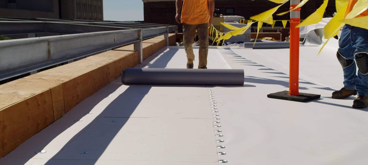 Construction workers roling out the EverGuard Extreme TPO by GAF. 