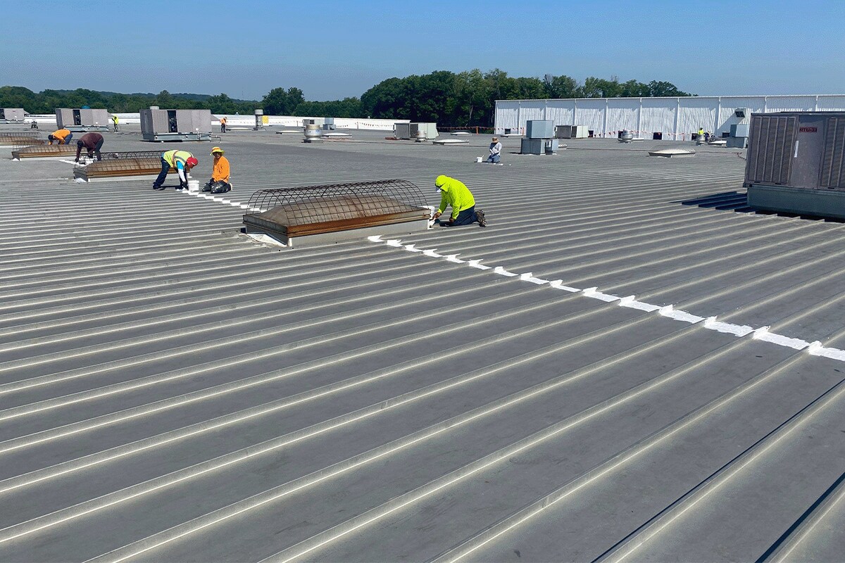 Roofing contractors preparing the metal roof of TOA USA for a GAF coatings restoration solution.