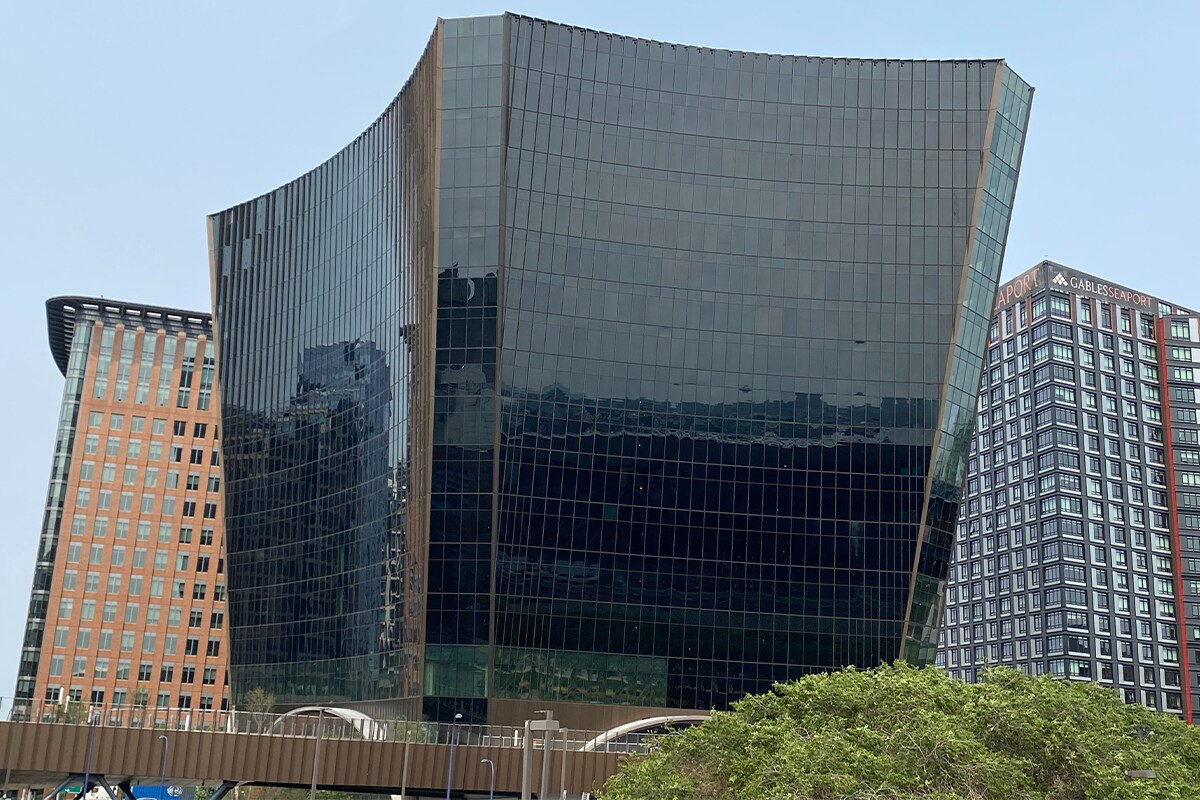 Curved 10 world trade glass skyscraper reflects sky, surrounded by modern buildings.
