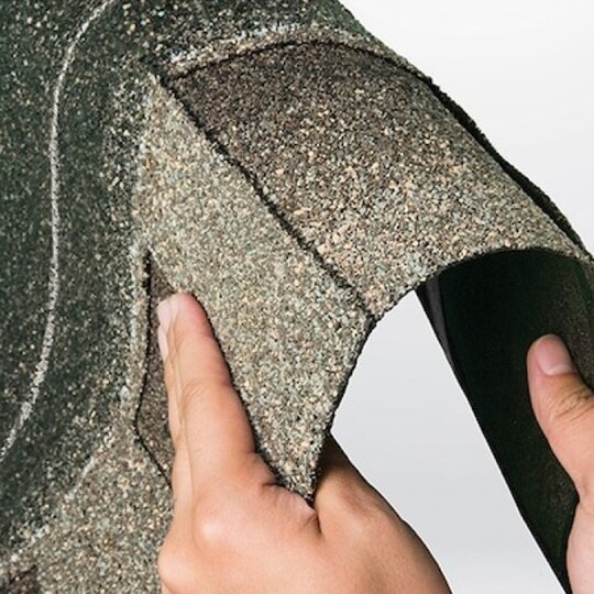 Hands bending a strip of Timberline ArmorShield II shingles, showing how flexible and durable it is.