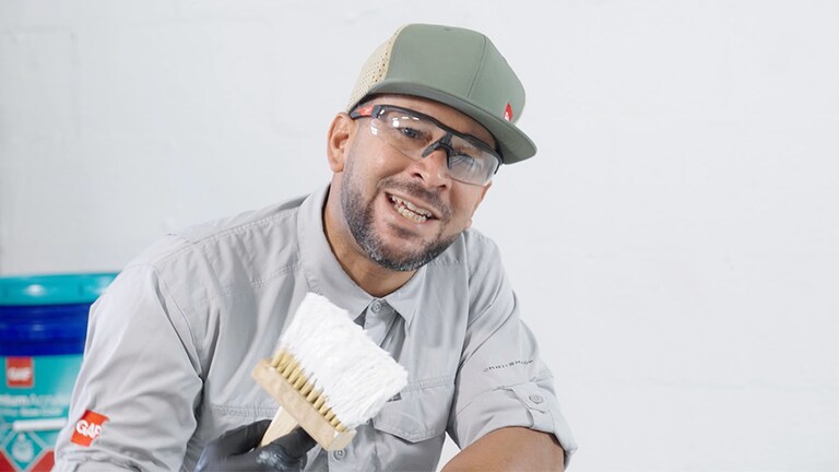 GAF worker holding a brush, demonstrating how to apply GAF  coatings products. 
