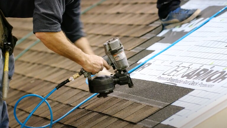 Contractor on roof nailing in new HDZ shingles in the LayerLock® StrikeZone® nailing area